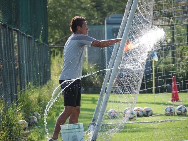 ゴール付近に打ち水をする藤吉信次コーチ。
