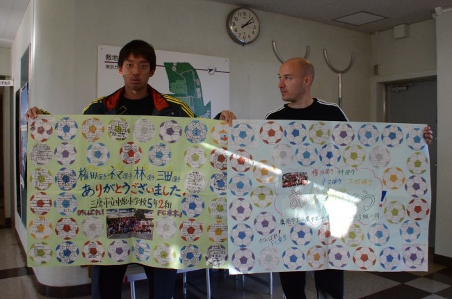 小学生から送られたお礼のメッセージを掲げる権田修一（左）、ネマニャ ヴチチェヴィッチ（右）